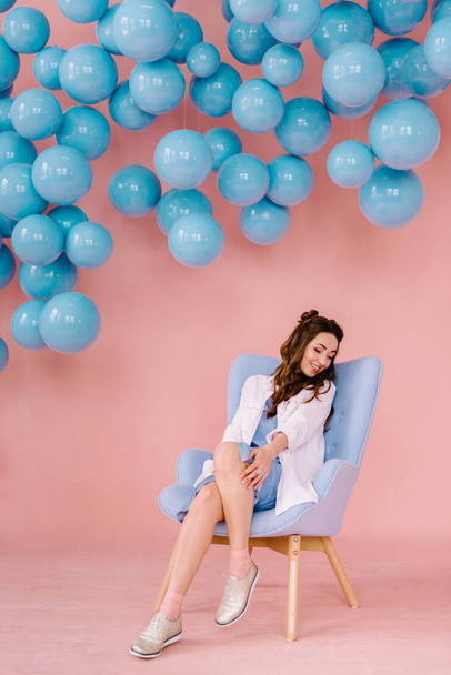 Hermosa chica en un vestido azul en una habitación rosa con bolas azules y
 - Foto, Imagen