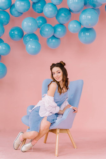 Menina bonita em um vestido azul em uma sala rosa com bolas azuis e
 - Foto, Imagem