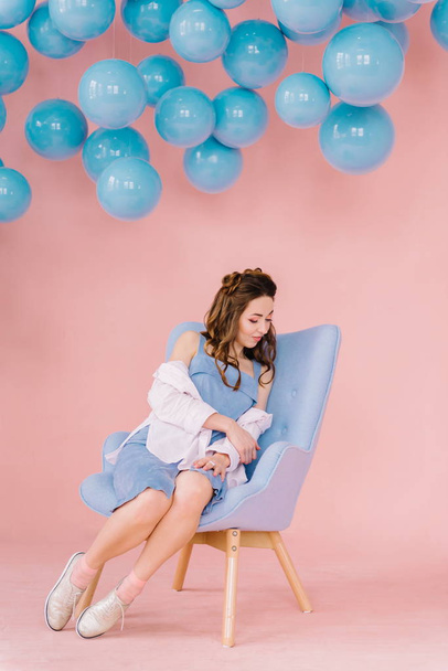 Menina bonita em um vestido azul em uma sala rosa com bolas azuis e
 - Foto, Imagem