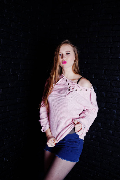 Studio shot of brunette girl at pink sweater with jeans shorts a - Foto, Imagen