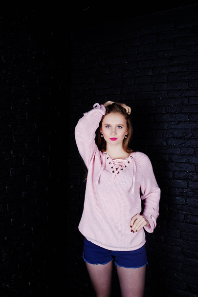 Studio shot of brunette girl at pink sweater with jeans shorts a - Fotografie, Obrázek