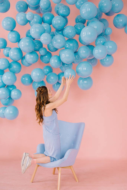 Une fille de petite taille dans une chambre rose joue avec la balle bleue
 - Photo, image