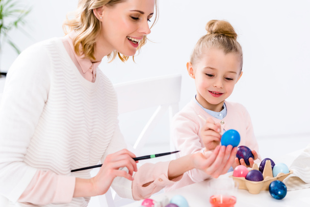Äiti auttaa tytärtä värittämään pääsiäismunia
 - Valokuva, kuva