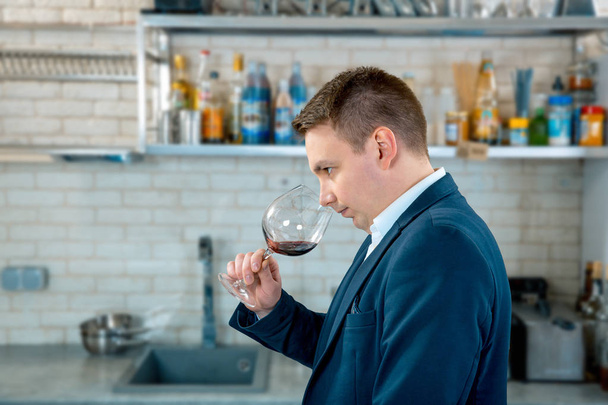 Vinař nebo sommeliérský sniffs červené víno ve sklenici na kuchyň interiér - Fotografie, Obrázek