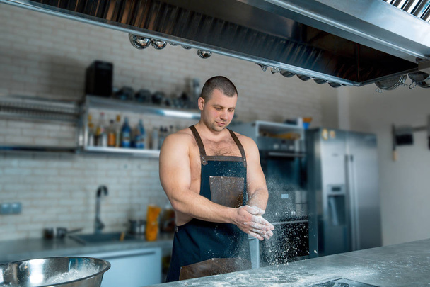 chef Cook bodybuilder batte le mani con la farina. processo di cottura
 - Foto, immagini