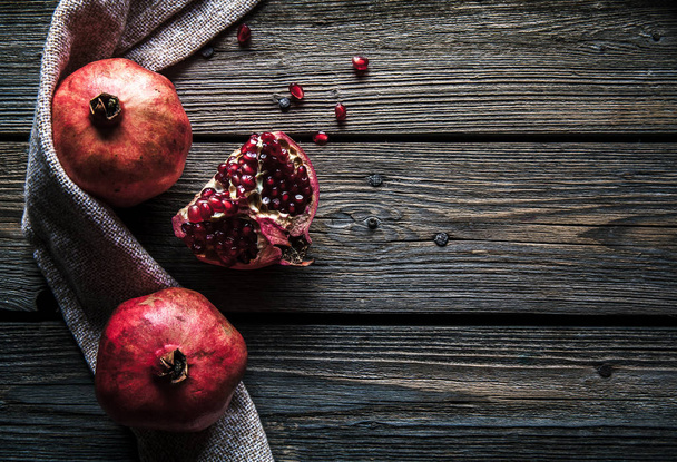 Ripe pomegranates, napkin and table knife on wooden background - Foto, afbeelding