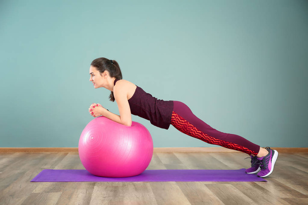 Beautiful young woman doing fitness exercise with ball at home - Photo, Image