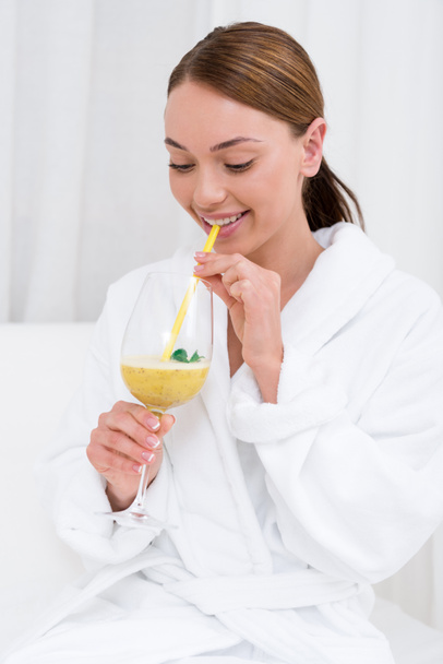 attractive young woman in white bathrobe with cocktail in spa salon - Photo, Image