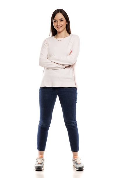 Young woman in jeans, blouse and sneakers on a white background - Photo, Image