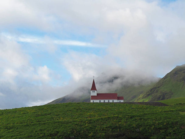 lonely red white church in vik in iceland green grass hills and  - Fotoğraf, Görsel
