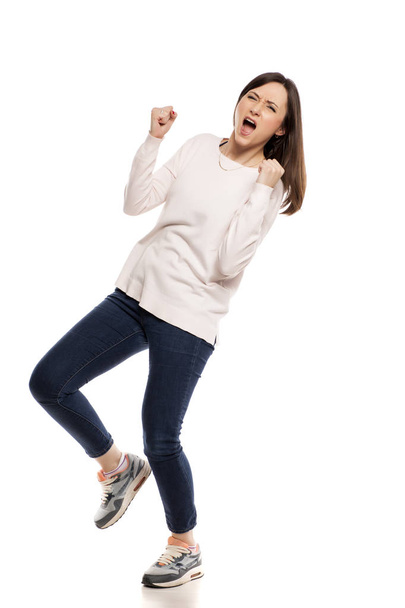 Mladá nadšená žena s Vítězné gesto na bílém pozadí - Fotografie, Obrázek