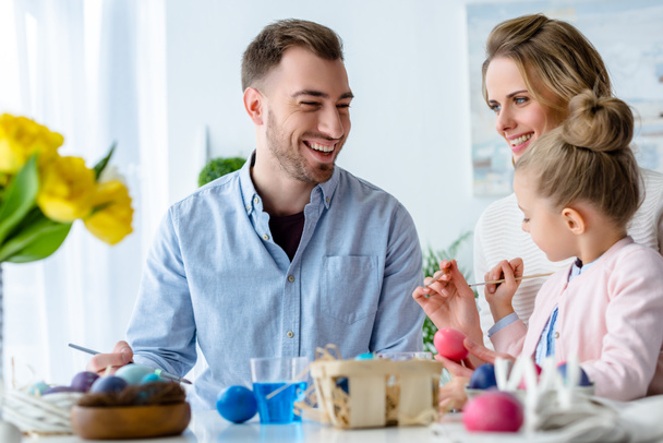 Smiling family having fun on Easter by table with painted eggs - Fotografie, Obrázek