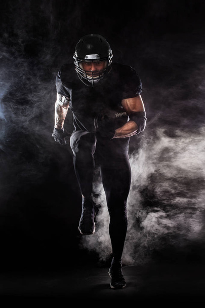 American football sportsman player isolated on black background - Foto, imagen
