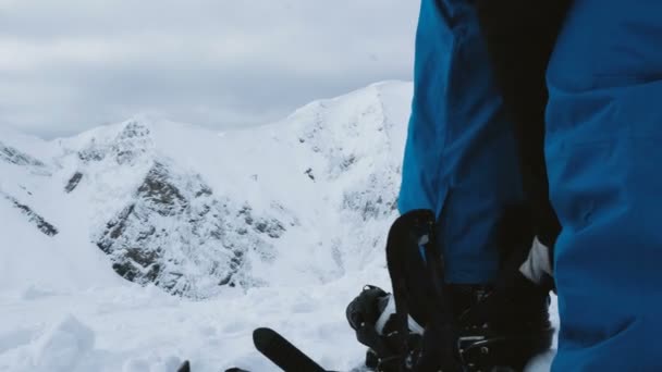 ein Snowboardermädchen zieht in den Bergen auf dem Berg Stiefel an, 4k. - Filmmaterial, Video
