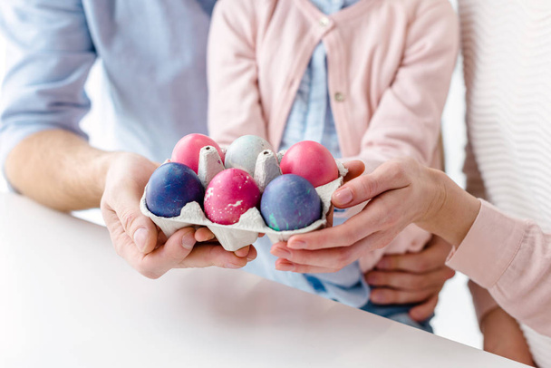Easter eggs in carton in hands of family with daughter - Photo, image
