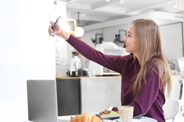 Young woman taking selfie in cafe - Φωτογραφία, εικόνα