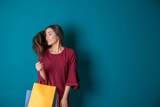 Schöne junge Frau mit Einkaufstaschen auf farbigem Hintergrund - Foto, Bild
