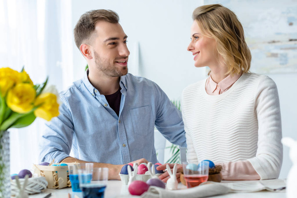 Smiling couple by table with painted Easter eggs - Φωτογραφία, εικόνα