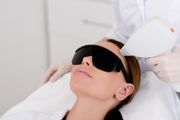 gedeeltelijke weergave van jonge vrouw ontvangen van laser hair removal epileren op gezicht in salon - Foto, afbeelding