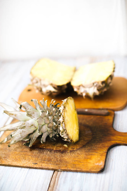 Ripe bisected ripe pineapple on a wooden background - Fotoğraf, Görsel