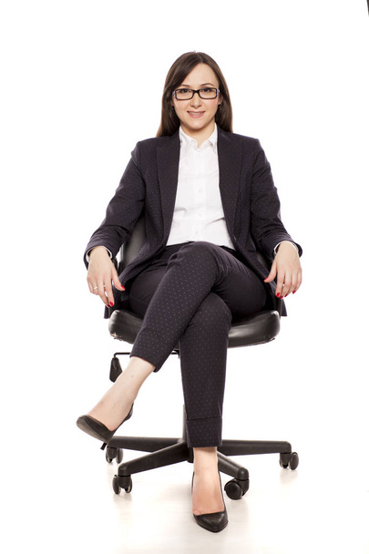 Lächelnde Geschäftsfrau im Bürostuhl posiert auf weißem Hintergrund - Foto, Bild