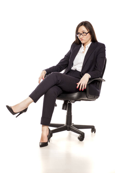 Unsatisfied businesswoman in an office chair posing on a white background - Zdjęcie, obraz