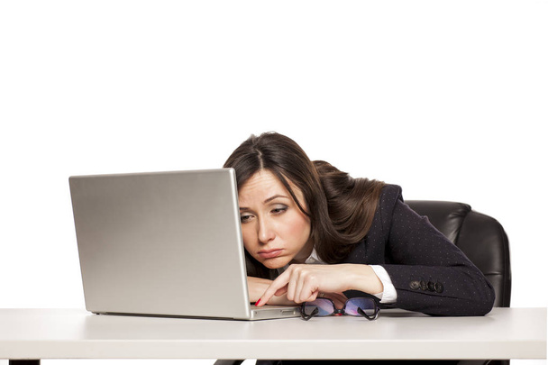Bir dizüstü bilgisayar ile bir masada çalışan genç yorgun iş kadın - Fotoğraf, Görsel