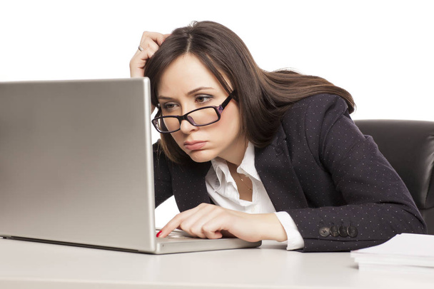 Молодая уставшая деловая женщина работает за столом с ноутбуком
 - Фото, изображение