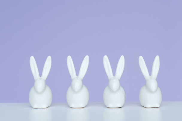 Rabbit statuettes in row on violet background - Photo, Image