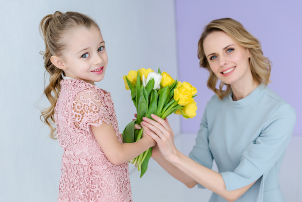 Mother and daughter holding bouquet of spring flowers on 8 march - 写真・画像