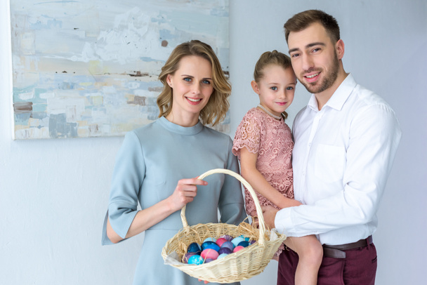 Οικογένεια γιορτάζει το Πάσχα με ζωγραφισμένα αυγά στο καλάθι - Φωτογραφία, εικόνα
