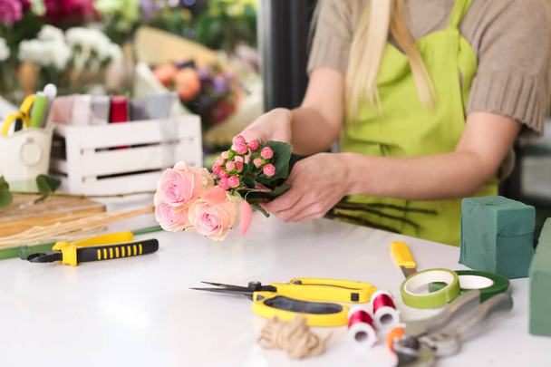 Female florist making beautiful bouquet in flower shop - Photo, image