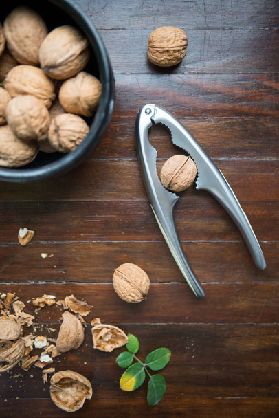 still life of walnuts with nutcracker on a wooden table, natural background, healthy concept, top view - Foto, Bild
