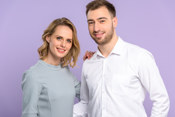 Young man and woman smiling isolated on violet - Fotoğraf, Görsel