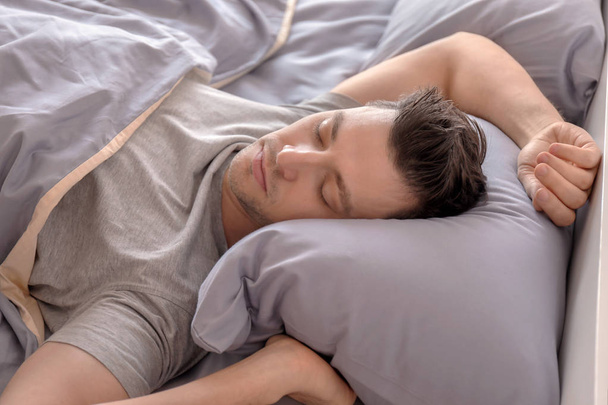 Young man sleeping in bed at home - Φωτογραφία, εικόνα
