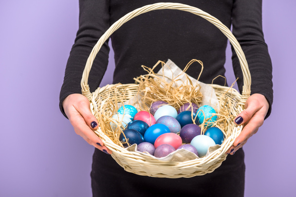 Woman with colored Easter eggs in basket isolated on violet - Foto, Imagem