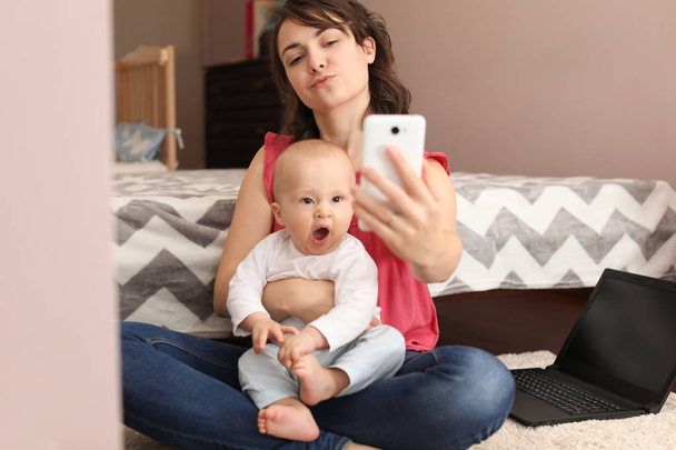 Young mother taking selfie with her cute baby at home - Foto, imagen
