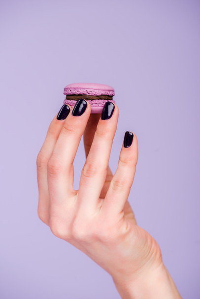Female hand with macaron isolated on violet - Φωτογραφία, εικόνα