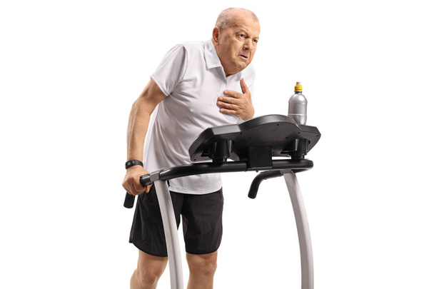 Senior exercising on a treadmill and having a heart attack isolated on white background - 写真・画像
