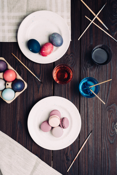 Velikonoční vajíčka a macarons na štítku na dřevěný stůl - Fotografie, Obrázek