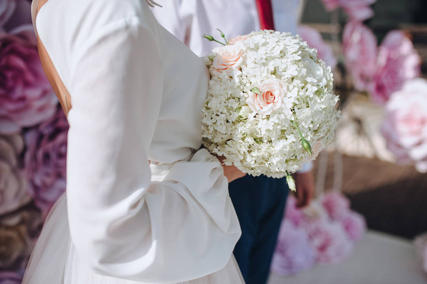 Крупним планом нареченої у весільній сукні, що тримає весільний букет, з соковитими квітами
 - Фото, зображення