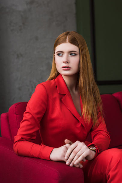 Stylish young woman with wristwatch dressed in red suit - Photo, Image
