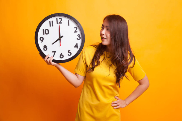 Young Asian woman with a clock in yellow dress - Fotó, kép