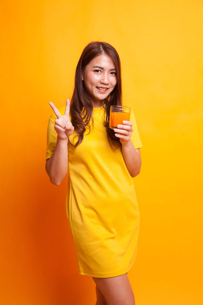 Young Asian woman show victory sign drink orange juice in yellow - Fotografie, Obrázek