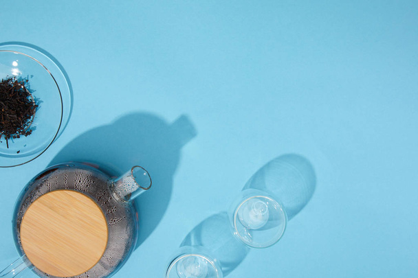 pohled shora konvice s čerstvým čajem, prázdných sklenic a suché bylinné čaje v misce na modré  - Fotografie, Obrázek