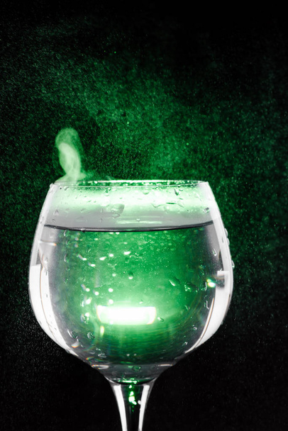 Still water in the wine glass with green background - Foto, imagen