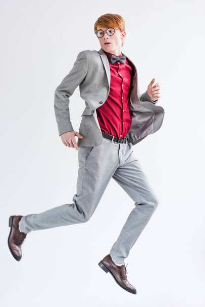 Jumping male fashion model dressed in suit isolated on grey - Fotó, kép