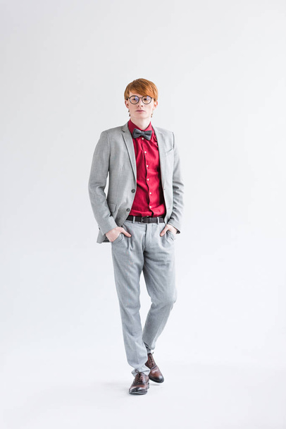 Young male fashion model in eyeglasses dressed in suit isolated on grey - Foto, Imagen