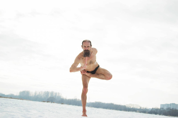 Ein Mann mittleren Alters macht Yoga auf einem zugefrorenen Fluss. vrishasa - Foto, Bild