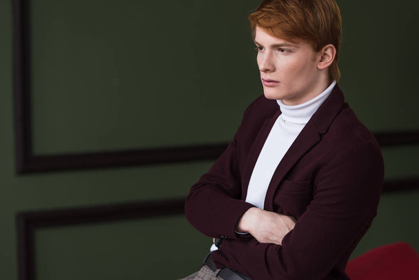 Side view of male model in jacket sitting on couch - Zdjęcie, obraz